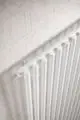 Nahaufnahme eines weißen Kermi Pio Bad- und Wohnheizkörpers an einer Betonwand.