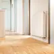Weißer Buderus-Heizkörper in kompakter Ausführung an einer hellen Wand, montiert in einem modernen Raum mit Holzfußboden. Heizungsventil am Heizkörper sichtbar.