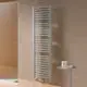 Vertikaler Kermi-Heizkörper mit gebogenen Längsrippen, montiert an einer hellen Wand, neben einem kleinen Tisch mit Pflegeprodukten.
