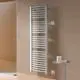 Kermi-Heizkörper, vertikal montiert, mit gebogenen Röhren vor einer hellen Wand im Badezimmer, neben einer stehlen Ablage mit Pflegeprodukten.