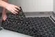 Kermi-Zubehör, bestehend aus mehreren modularen Elementen mit einem strukturierten Muster, wird gerade verlegt. Die Platten sind zur Verbesserung der Drainage und Isolierung gedacht.