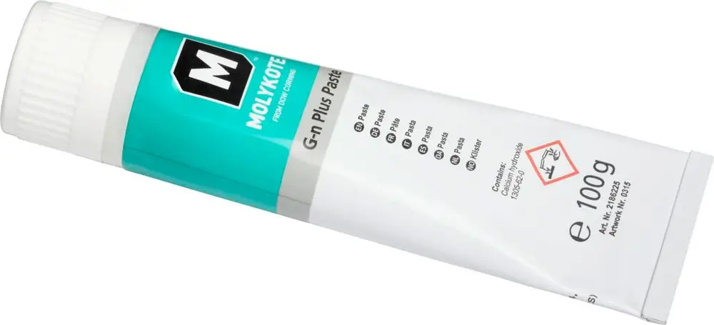 Tube mit grauem Schmiermittel, erhältlich in 100 g, mit der Aufschrift "Molycote". Auf dem Etikett sind Sicherheitshinweise und Inhaltsstoffe aufgeführt.