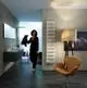 Zehnder-Heizkörper in modernem Badezimmer, vertikal montiert an einer Wand, neben einem Waschbecken und einem stilvollen Sessel.