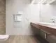 Weißer Elektroheizkörper von Zehnder an der Wand, neben einem modernen Waschbecken und Handtuchhalter, in einem hellen, modernen Badezimmer.