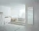 Zehnder Heizkörper in weiß, vertikal montiert an einer Wand, mit Handtuchhalter, neben einer modernen Badewanne in einem hellen Raum.