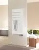 Zehnder Heizkörper in Weiß, vertikal angebracht, mit horizontalen Lamellen und einem Handtuch. Im Badezimmer mit hellen Wänden und einem Holzstuhl im Hintergrund.