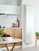 Vertikaler weißer Purmo-Heizkörper mit Längsrippen, montiert an einer hellen Wand in einer modernen Küchenumgebung.