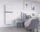 Purmo-Heizkörper in modernem Design, vertikal montiert an der Wand, mit einer minimalistischen Oberfläche. Nachtisch mit Bücherregal und gedecktem Bett im Raum.