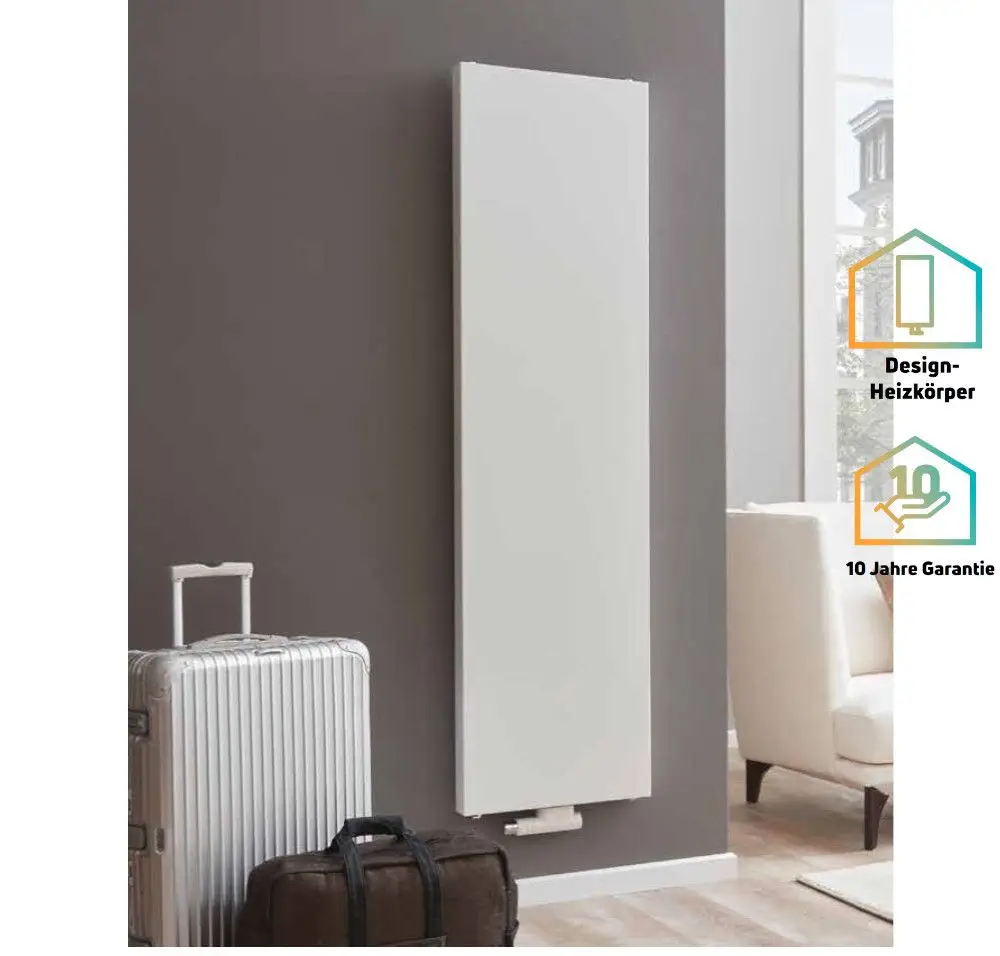 Vertikaler Heizkörper von Purmo, weiße glatte Oberfläche, an einer hellen Wand montiert. Neben dem Heizkörper steht ein Koffer und eine Couch ist im Hintergrund sichtbar.