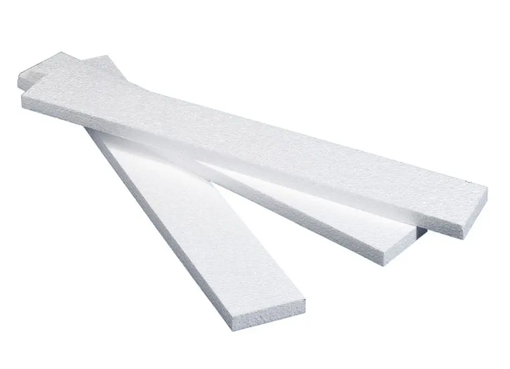 Mehrere weiße Dämmstreifen aus expandiertem Polystyrol, die in einem Raum arrangiert sind, möglicherweise für die Verwendung in Verbindung mit Purmo-Produkten.