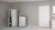 Viessmann Wärmepumpe in einem Raum, montiert neben einem Kühlschrank und einem weiteren technischen Gerät. Helle Wände und Fenster sorgen für Tageslicht.