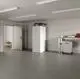 Weißer Speicher von Stiebel Eltron in einem modernen Raum, neben einer Werkbank mit Werkzeugen und einem geöffneten Raum mit einem Sofa im Hintergrund.