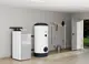 Stiebel Eltron Wärmepumpe in einem modernen Raum, kombiniert mit einem weißen Warmwasserspeicher. Im Hintergrund sind Reinigungswerkzeuge an der Wand befestigt.