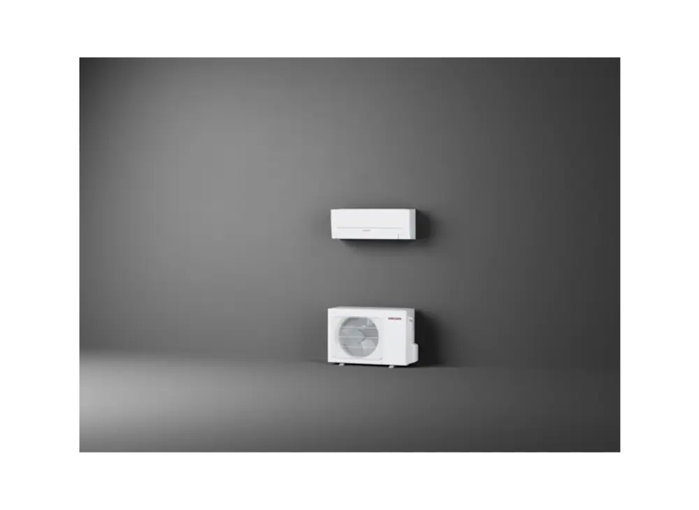 Split-Klimagerät von Stiebel Eltron, bestehend aus einer Wandinneneinheit und einer Außeneinheit, montiert an einer grauen Wand mit neutralem Boden.