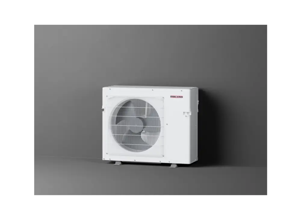 Weißes Außengerät von Stiebel Eltron mit großer Lüfteröffnung, auf einem stabilen Untergestell, vor grauer Wand positioniert.