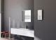Weißer Durchlauferhitzer an einer grauen Wand, montiert neben einem Waschbecken mit Wasserhahn und Spiegel. Markenlogo von Stiebel Eltron sichtbar.