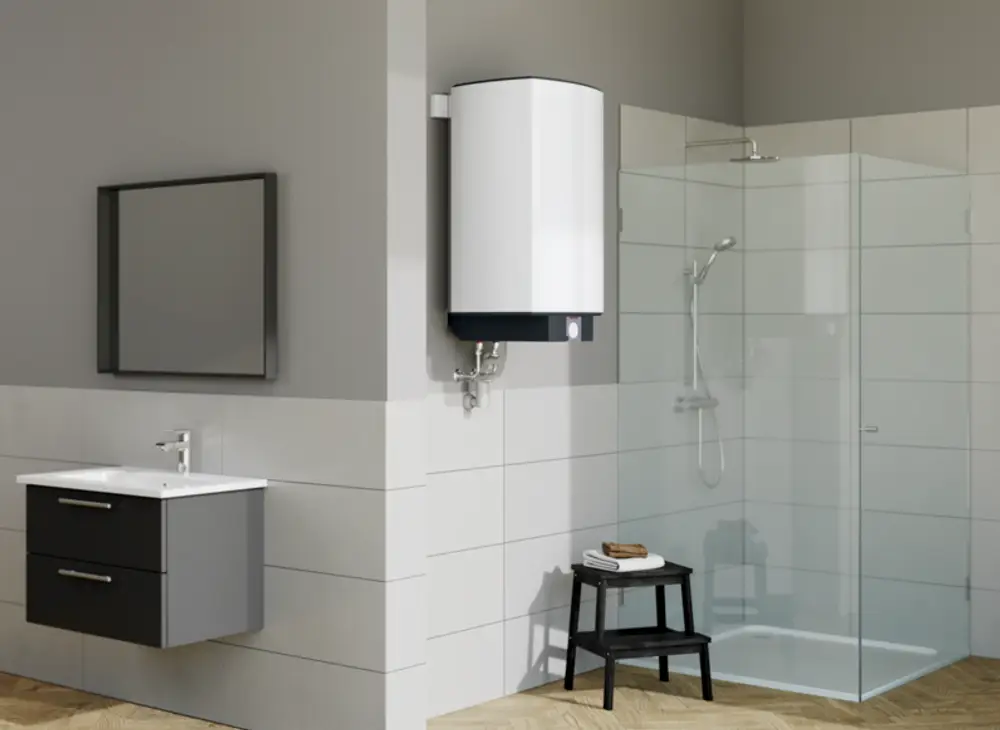 Stiebel Eltron Warmwasser-Wandspeicher in einem modernen Badezimmer, montiert an der Wand, neben einem Waschtisch mit Spiegel und einer Duschkabine. Holzfußboden sichtbar.