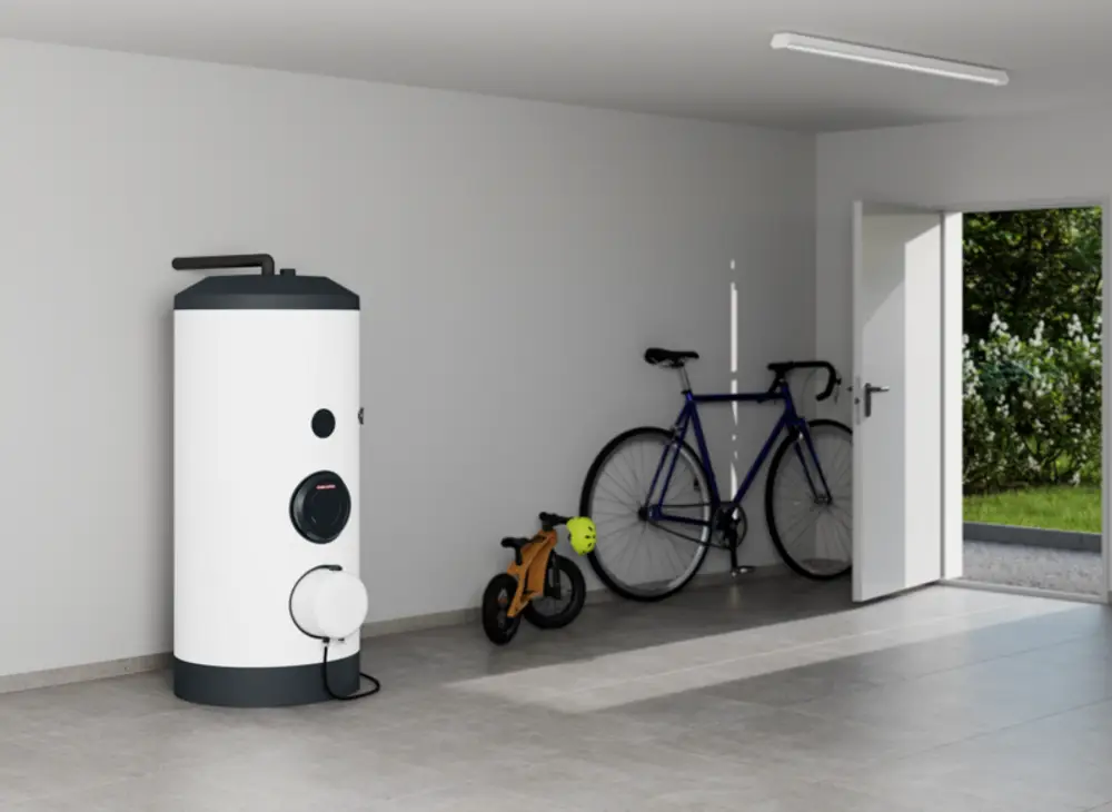 Weißer Kombi-Standspeicher von Stiebel Eltron in einem Garagenraum. Daneben stehen ein Fahrrad und ein kleiner Kinderwagen. Die Tür zum Außenbereich ist geöffnet.