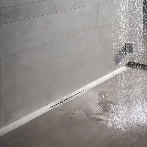 Graue Wand- und Bodenfliesen mit einem modernen Ablaufsystem, aus dem Wasser herunterläuft, und sichtbar Wasserpfützen auf dem Boden.