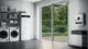 Buderus Inneneinheit mit integriertem Warmwasserspeicher und Funkmodul, positioniert in einem modernen Raum mit Waschmaschinen und Fenstertür zum Garten.