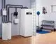 Heizgerät Buderus mit integriertem Warmwasserspeicher und Leitungsanschlüssen in einem modernen Raum, kombiniert mit Fitnessgeräten und Trainingsmatte.