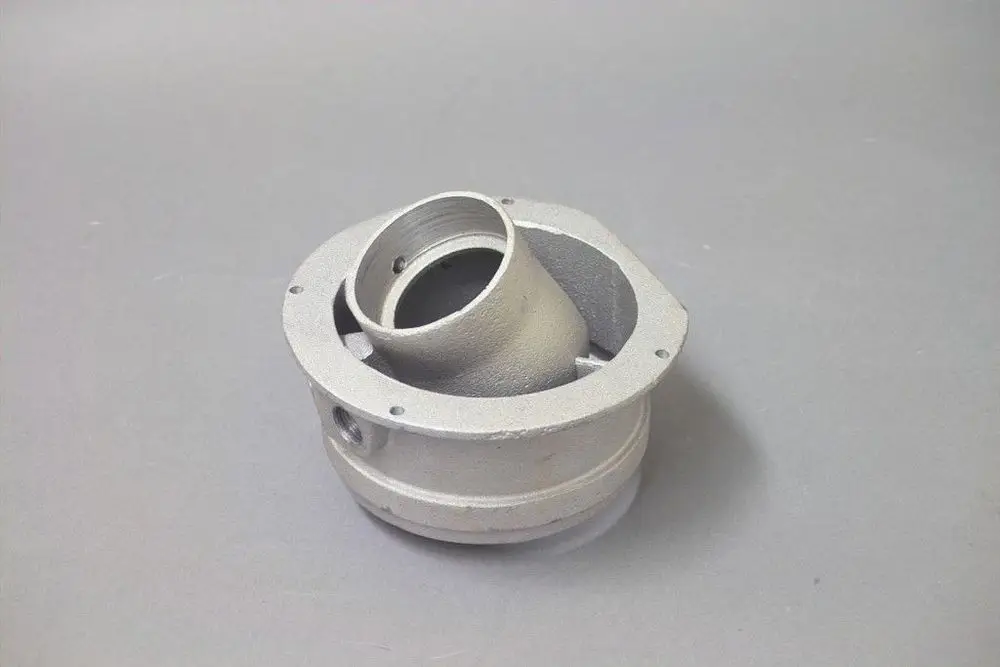 Abgasadapter von Brötje, aus Metall, mit einer Rundöffnung und mehreren Befestigungslöchern, auf grauem Hintergrund.