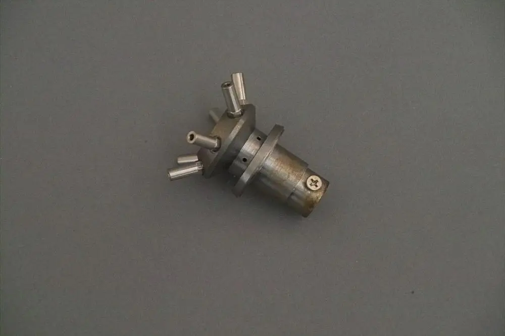 Gaskopf von Brötje, metallisches Bauteil mit mehreren Anschlüssen, zentraler Halterung und schraubbaren Elementen, auf grauem Hintergrund abgebildet.