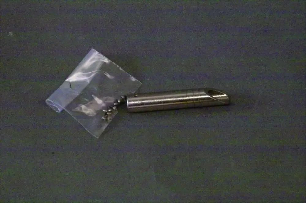 Gaskopf von Brötje, aus Metall, abgerundete Form, neben einer durchsichtigen Tüte mit kleinen Schrauben auf einem grauen Untergrund.
