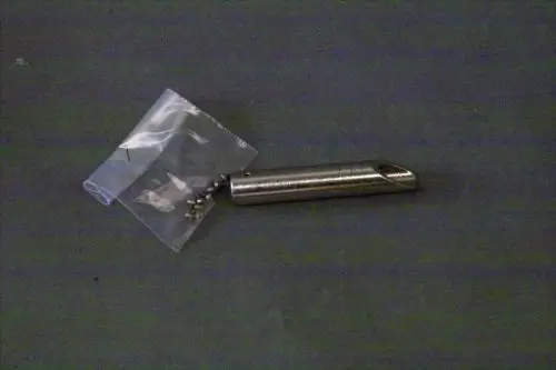 Gaskopf von Brötje, aus Metall, abgerundete Form, neben einer durchsichtigen Tüte mit kleinen Schrauben auf einem grauen Untergrund.