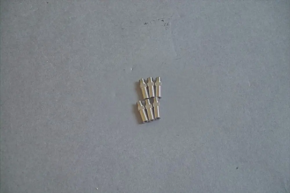 Brötje Gaskopf-Düse aus Metall, bestehend aus mehreren Einzelteilen, auf grauem Hintergrund. Die einzelnen Düsen sind gleichmäßig angeordnet.