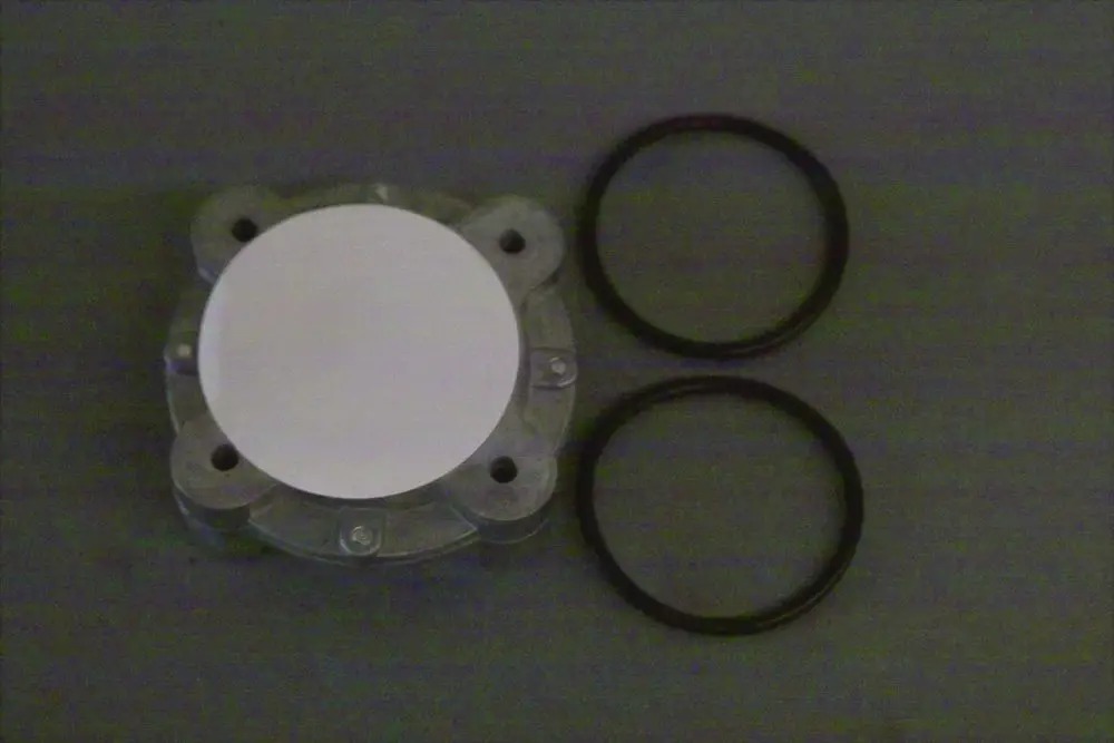 Gasfilter von Brötje, bestehend aus einem runden, flachen Teil mit zwei O-Ringen. Teile auf grauem Hintergrund angeordnet.