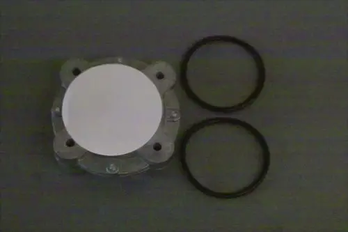 Gasfilter von Brötje, bestehend aus einem runden, flachen Teil mit zwei O-Ringen. Teile auf grauem Hintergrund angeordnet.