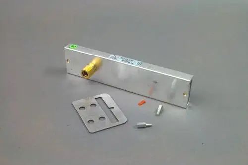 Umbausatz aus Metall mit einem Anschlussstück, einer flachen Platte und zwei kleinen Verbindungsteilen, wahrscheinlich für Gasgeräte von Brötje.