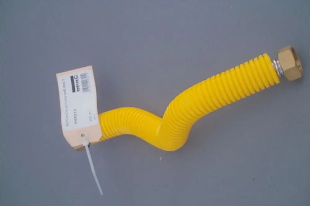 Gelber, flexibler Schlauch mit Spiralmuster und einer metallischen Verbindung. An einer Seite ist ein Produktetikett sichtbar. Verwendung im Gasbereich, möglicherweise von Brötje.