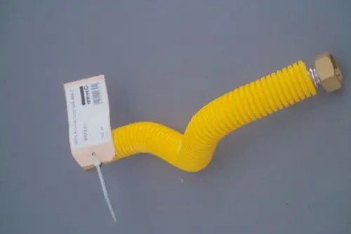 Gelber, flexibler Schlauch mit Spiralmuster und einer metallischen Verbindung. An einer Seite ist ein Produktetikett sichtbar. Verwendung im Gasbereich, möglicherweise von Brötje.