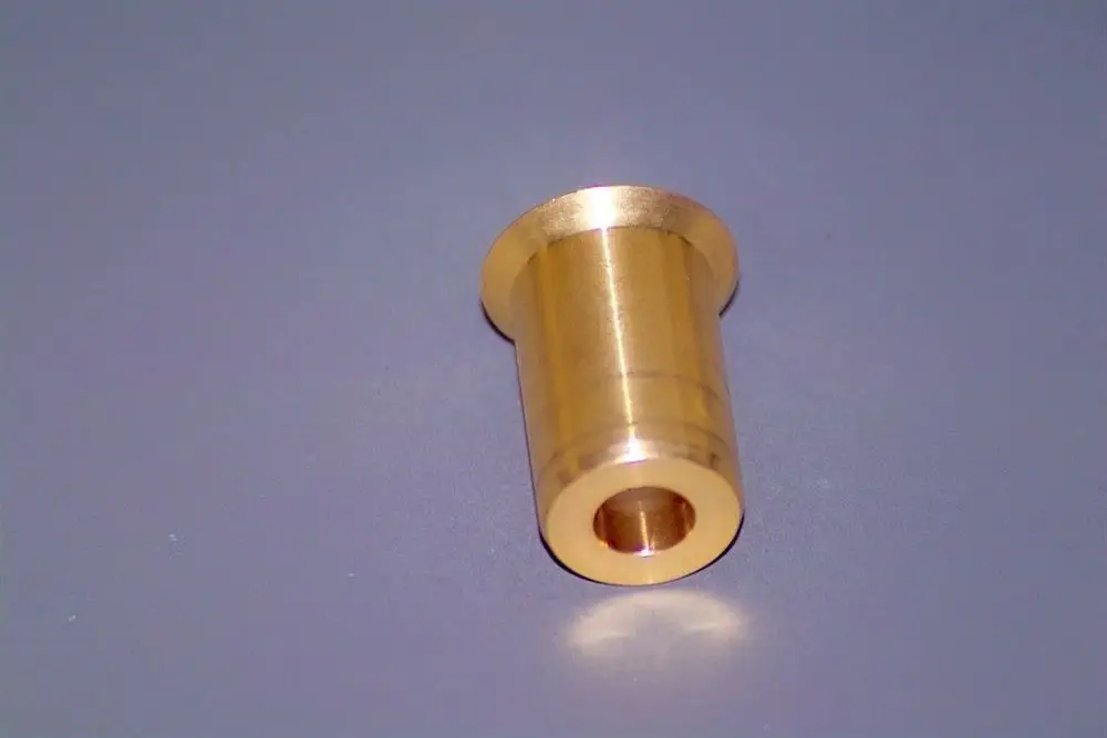 Brötje Düse aus Messing mit zylindrischer Form und einer durchgehenden Bohrung, liegt auf einem glatten Untergrund.