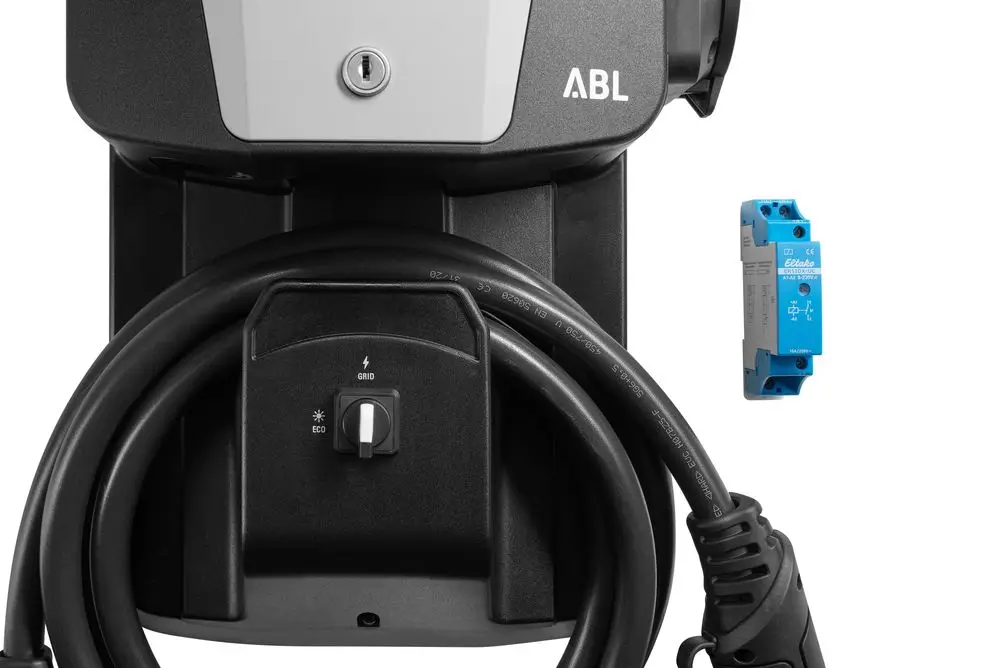 Ladeeinheit von ABL mit flexibler Kabelwicklung, integriertem Wahlschalter zur PV-Anbindung und einer elektronischen Komponente neben dem Ladegerät sichtbar.