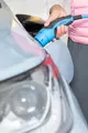 Hand hält einen blauen Ladestecker von MENNEKES, der in das Ladegerät eines Elektrofahrzeugs eingesteckt wird, während die Rückleuchte des Fahrzeugs im Fokus ist.