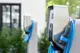 Mennekes Ladestation für Elektrofahrzeuge mit einem Kabel, montiert an einer Betonstütze, umgeben von grünen Pflanzen und einem modernen Gebäude im Hintergrund.
