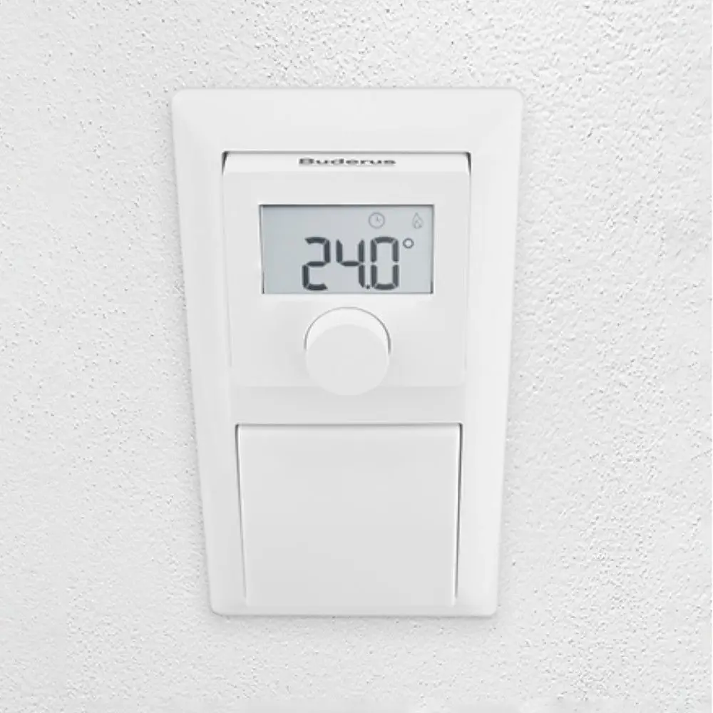Buderus Raumtemperaturregler mit digitaler Anzeige, aktueller Temperatur von 24°C und Einstellknopf, montiert an einer weißen Wand.