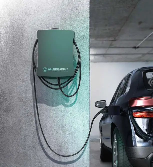 Wandmontierte Ladestation von Walther für Elektrofahrzeuge, verbunden mit einem schwarzen Auto. Kabel hängen an der grauen Wand.