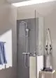 Grohe Duschsystem mit Regen- und Handbrause, an der Wand montiert, in Chromoptik. Dusche in einem modernen Badezimmer mit Glasabtrennung und Handtuchhalter.