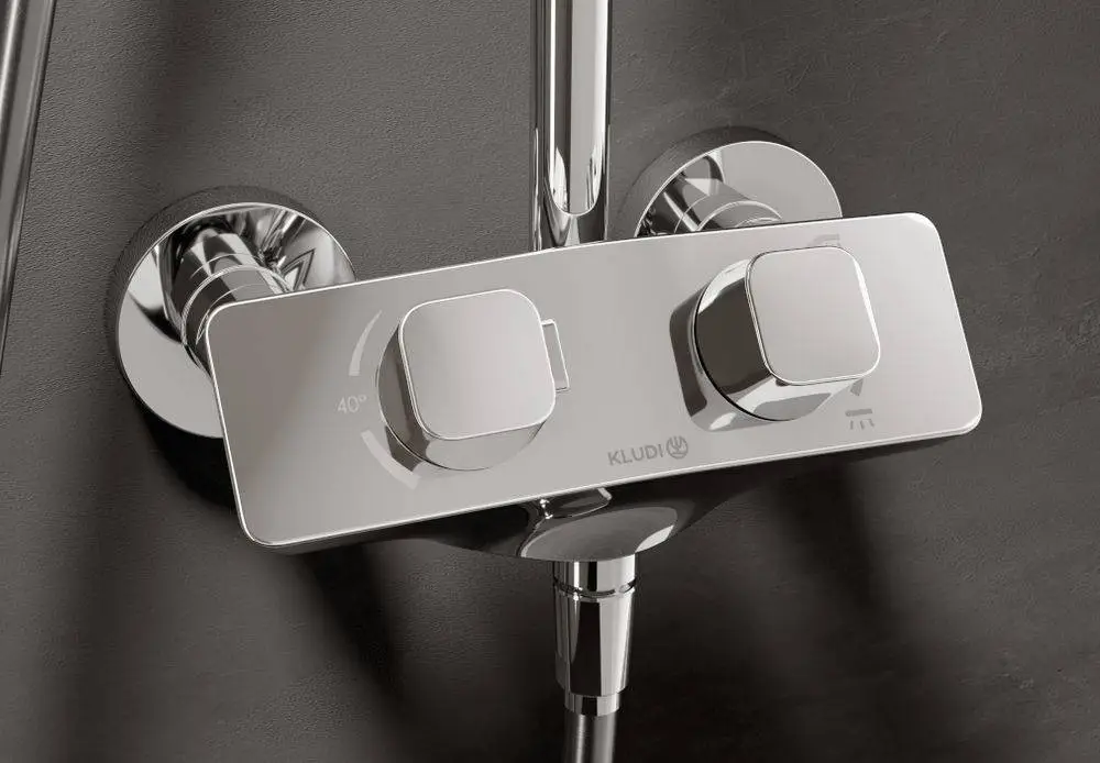 Thermostat für eine Dusche von Kludi, mit zwei Drehreglern zur Temperatureinstellung und Wasserflusskontrolle, montiert an einer dunklen Wandoberfläche.