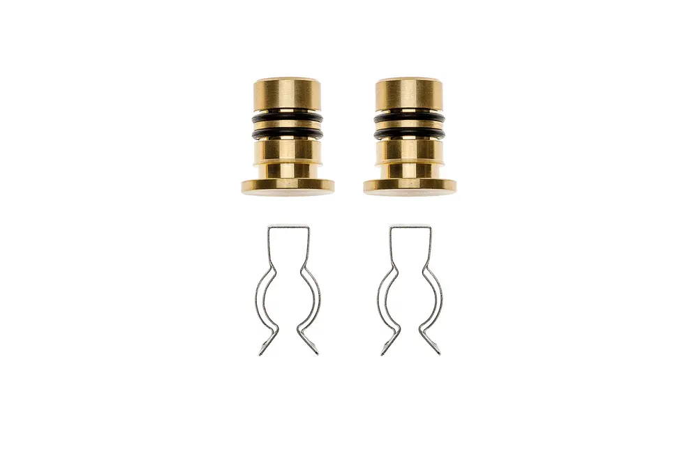 Set mit zwei goldfarbenen Bauteilen und zwei Federclips, die möglicherweise Teil eines Heizkolllektors von Brötje sind. Klar strukturierte Anordnung auf hellem Hintergrund.