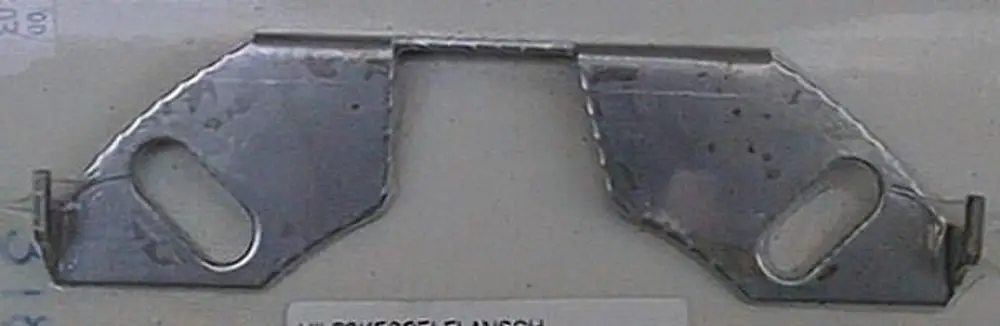 Metallischer Flansch mit zwei runden Aussparungen und seitlichen Befestigungselementen. Teil eines Brötje Systems zur Verbindung und Befestigung.