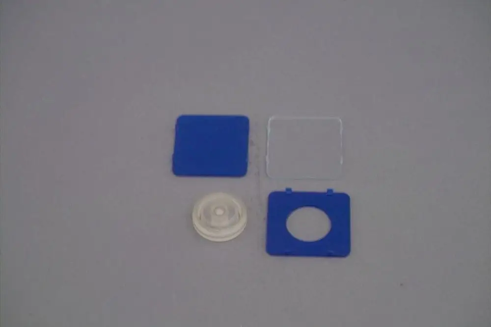 Brötje Schauglas mit zwei blauen Abdeckungen und einer klaren Linse in der Mitte, auf grauem Hintergrund angeordnet.