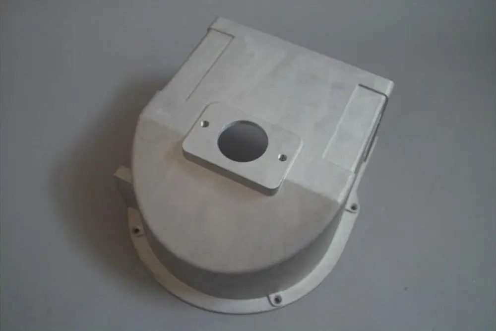 Aluminiumgehäuse mit runder Ansaugöffnung und rechteckigem Flansch, geeignet für Brötje-Produktanwendungen, auf grauem Untergrund.