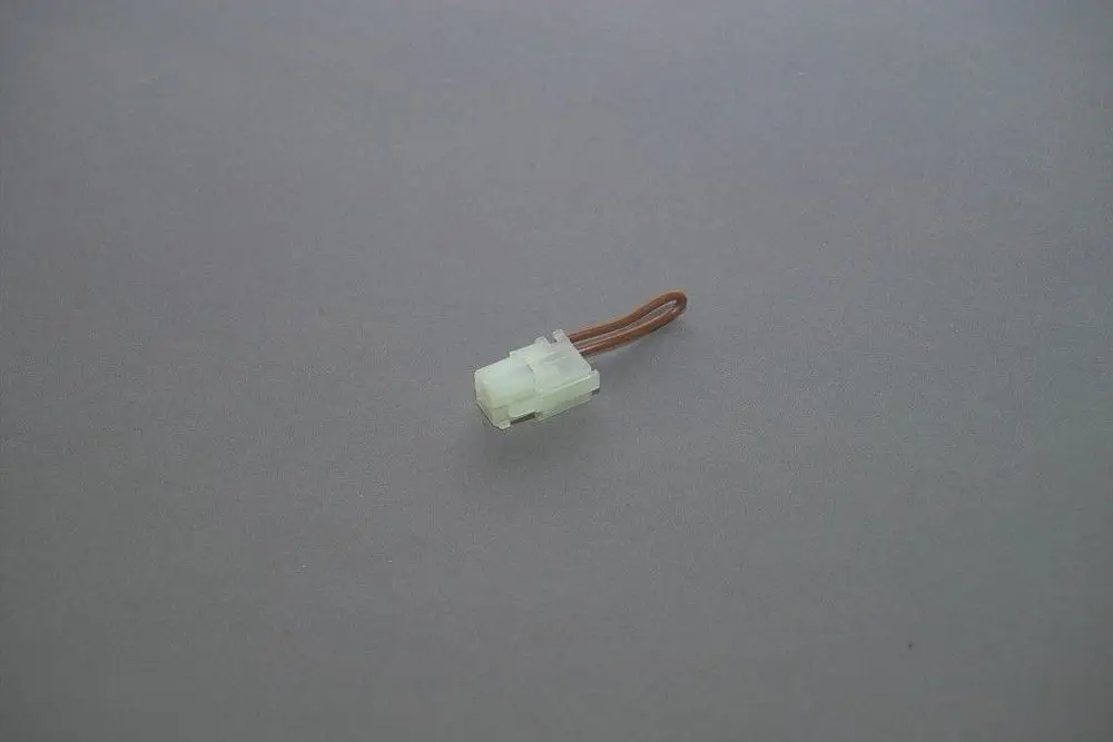 Brötje Brückenstecker mit einem transparenten Gehäuse und einem braunen Kabel. Der Stecker ist klein und besitzt eine geformte Verbindung für Elektroinstallationen.