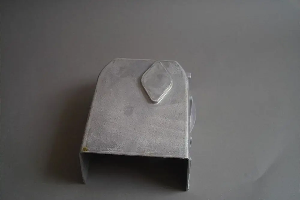 Metallische Ansaugöffnung von Brötje, rechteckig, mit abgerundeten Kanten und einem seitlichen Element. Oberfläche glänzend und leicht erhaben.
