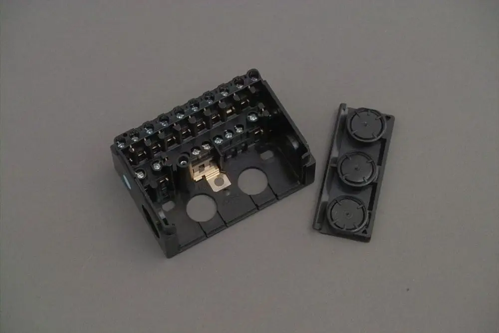 Brötje Sockel mit mehreren Anschlussklemmen und abnehmbarem Gehäuseteil, geeignet für elektrische Verbindungen. Schwarzes Kunststoffgehäuse.